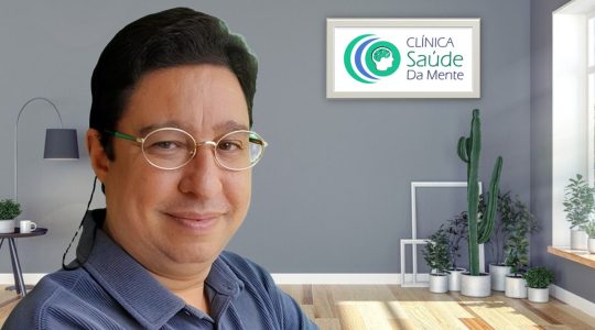 Roger, Psicanalista, homem de pele clara, cabelos curtos e escuros, com óculos pequenos, um leve sorriso e camisa azul.