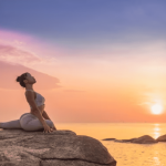 Mulher jovem praticando Yoga ao ar livre nas pedras em frente a praia