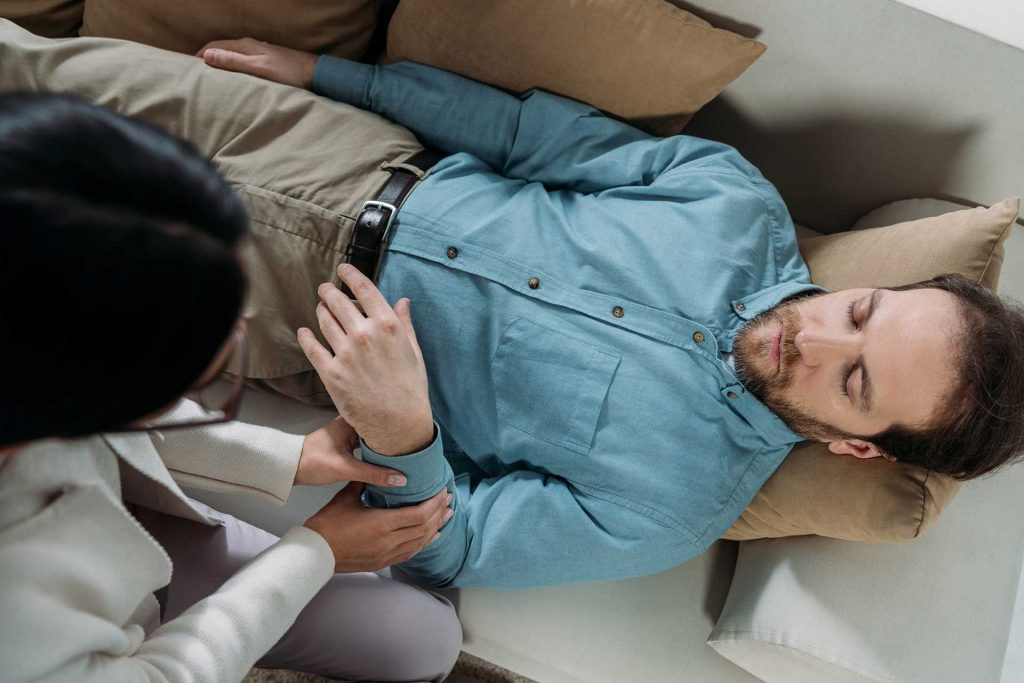 Terapeuta conduzindo sessão de hipnoterapia com paciente.